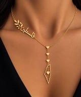 Woman wearing layered gold necklace with Arabic nameplate, chain links, and pendant with heart charm and geometric shape