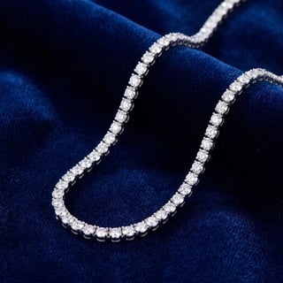 Silver tennis necklace with round cubic zirconia stones displayed on dark blue velvet fabric