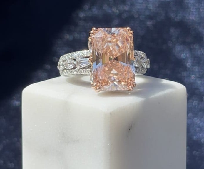 Luxury diamond ring with large peach-colored radiant cut stone and white metal band