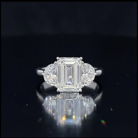 Platinum engagement ring with emerald-cut diamond center stone and oval diamond side stones