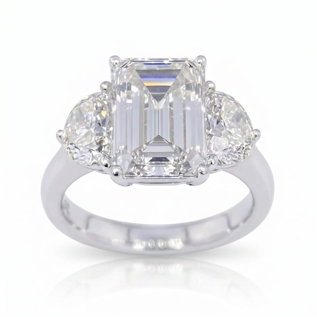 Platinum engagement ring with emerald-cut diamond center stone and pear-shaped side diamonds on white background