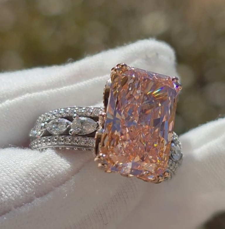 Luxury ring with large orange-brown cushion-cut diamond held in white-gloved hand
