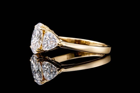 Gold engagement ring with large pear-shaped diamond on black reflective surface