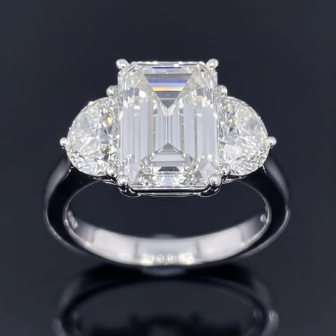 Platinum engagement ring with emerald-cut diamond center stone flanked by pear-shaped diamonds