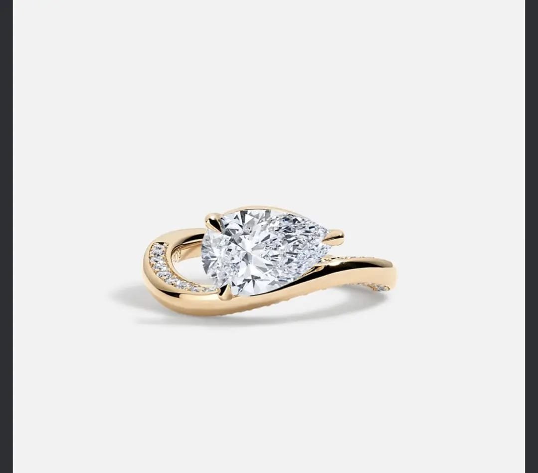 Gold engagement ring with large cushion-cut diamond and diamond-accented band on white background