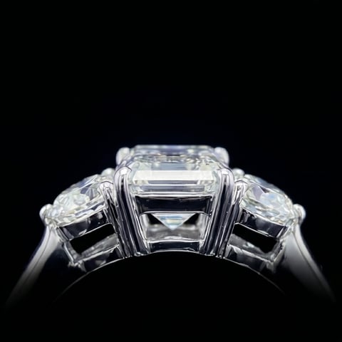 Three-stone diamond engagement ring with emerald-cut center stone and round side stones