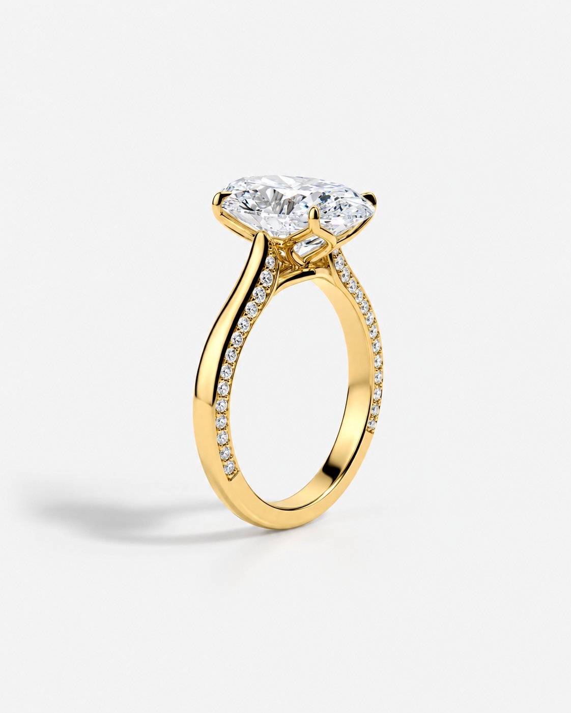 Gold engagement ring with oval diamond solitaire and pavé diamond band on white background