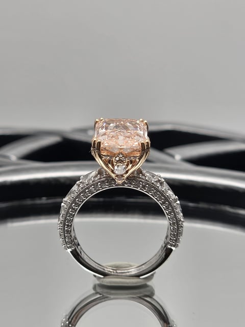 Elegant engagement ring with champagne diamond on ornate silver band displayed on black and white striped surface
