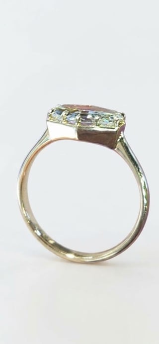 Gold engagement ring with rectangular cut diamond on white background