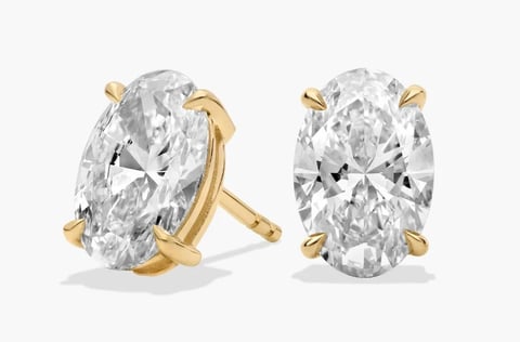Pair of oval-cut diamond earring mountings in gold settings shown from front and side views